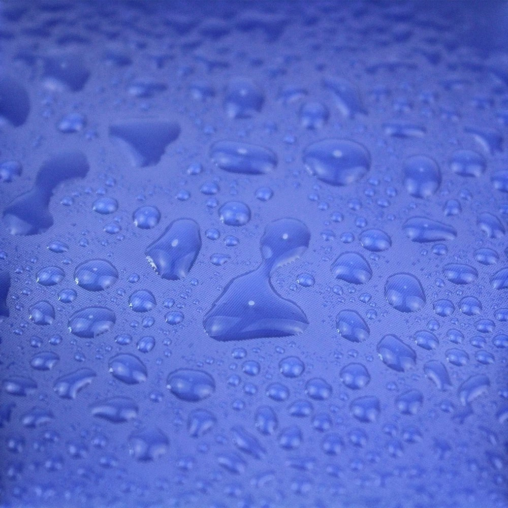 Gros plan sur le tissu bleu imperméable AventureCanine avec des gouttes de pluie perlées sur la surface