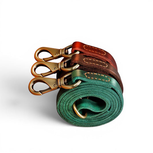 Trois laisses pour chien AventureCanine en cuir véritable souple, enroulées, coloris vert, marron et rouge.